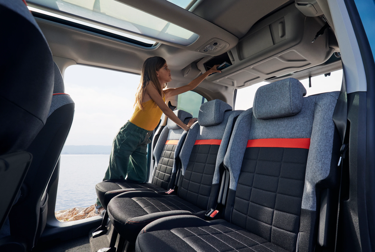 Achterinterieur van de Citroën Berlingo, met zicht op de tweede rij stoelen, ruime beenruimte en opbergvakken, geschikt voor passagiers of bagage