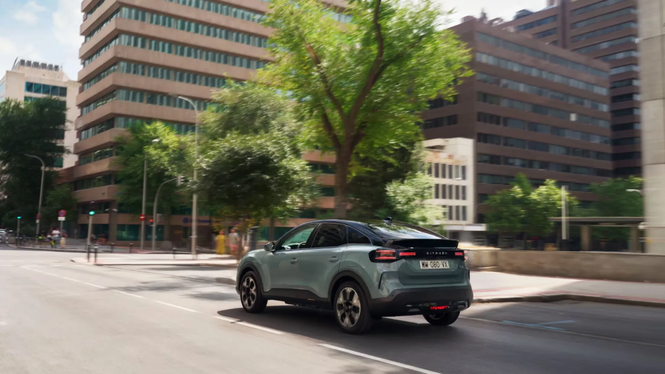 Zijaanzicht van de rijdende Citroën ë-C4 op de weg, met duidelijk zicht op de vloeiende lijnen en moderne vormgeving.