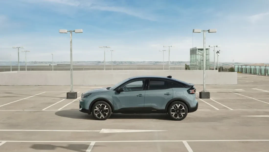 Zijaanzicht van de Citroën ë-C4, geparkeerd, met zicht op de portieren, ramen en gestroomlijnde carrosserie.